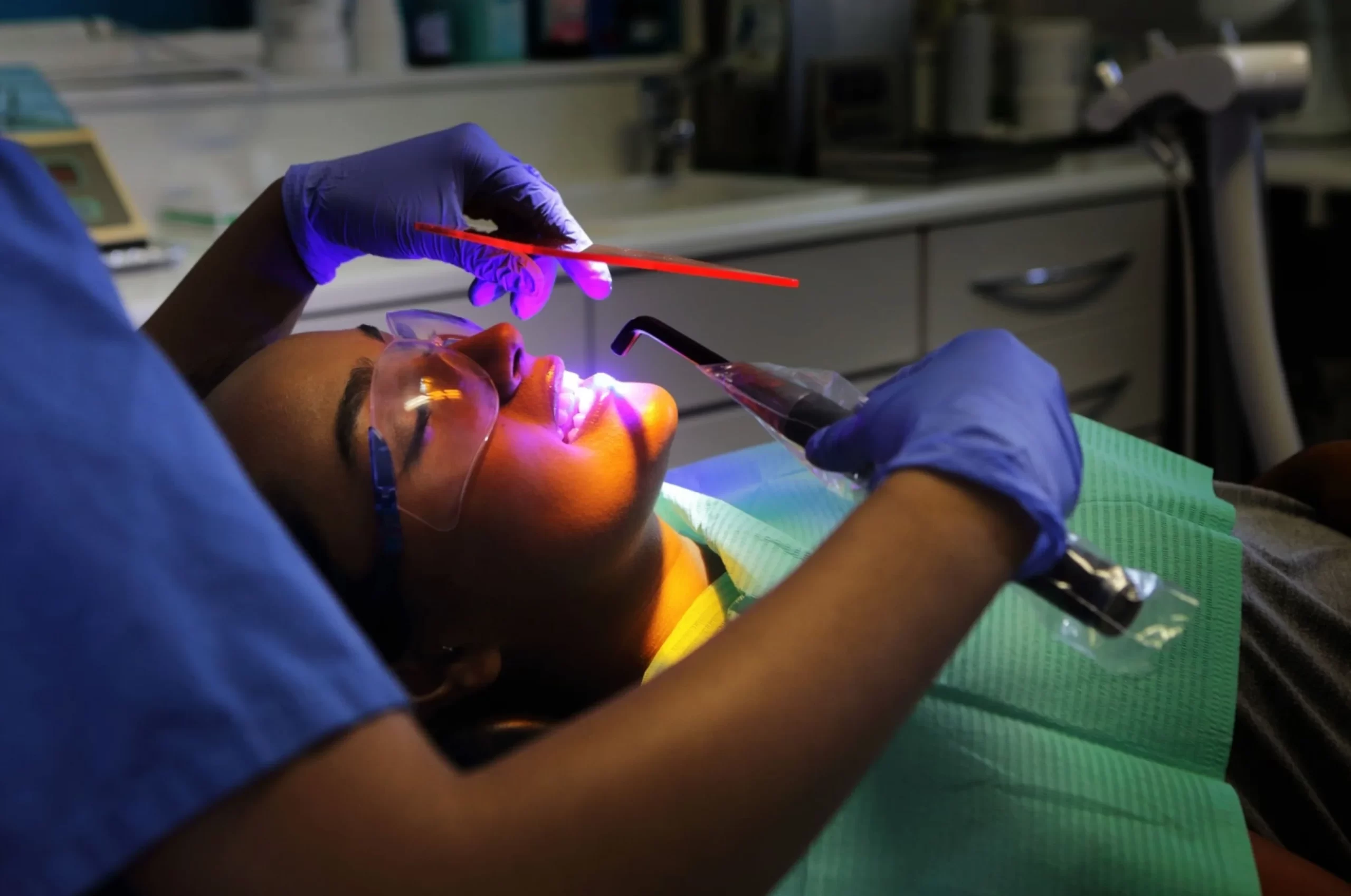 Doctor flashing a blue light a patient's teeth