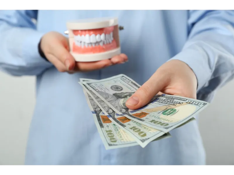 Doctor holding teeth prop and money